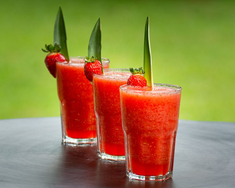 Three glasses of strawberry gazpacho garnished with a strawberry