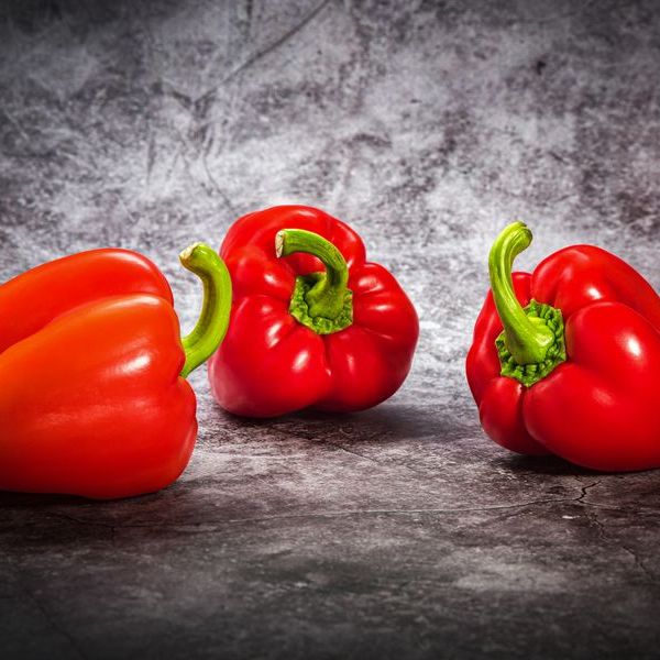Three red peppers on a stone surface