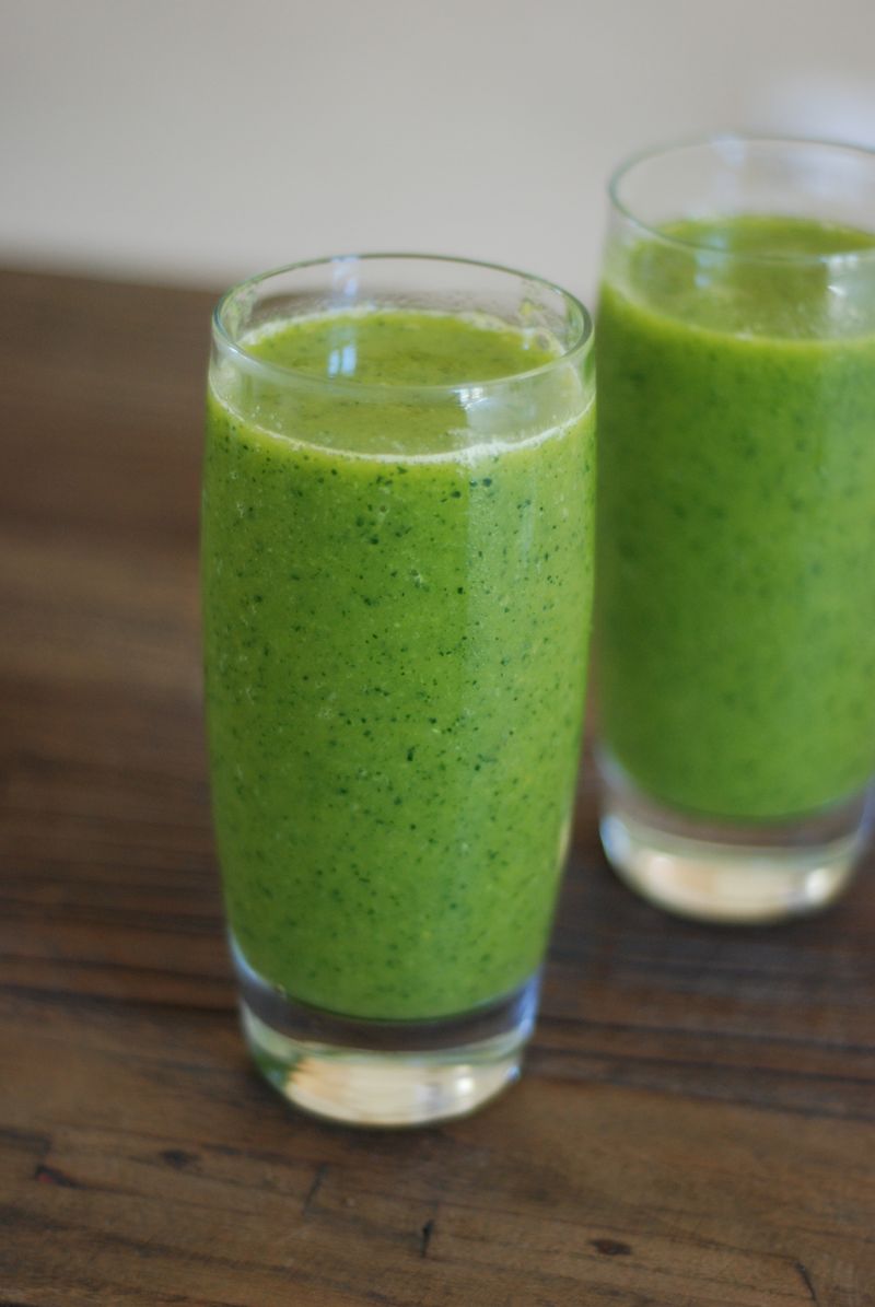 Two glasses of green smoothie on a wooden table